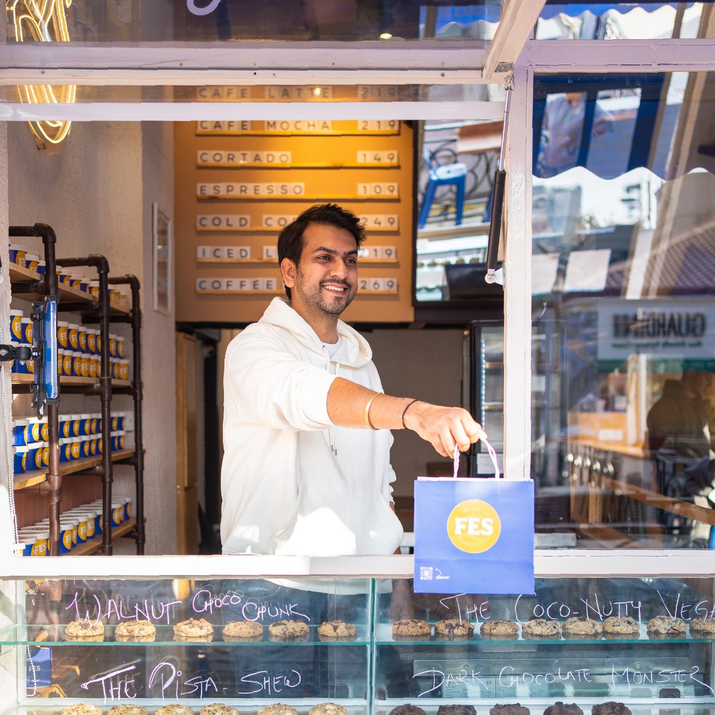 The FES counter at Galleria Market — cookies named in chalk, cups stacked to the ceiling