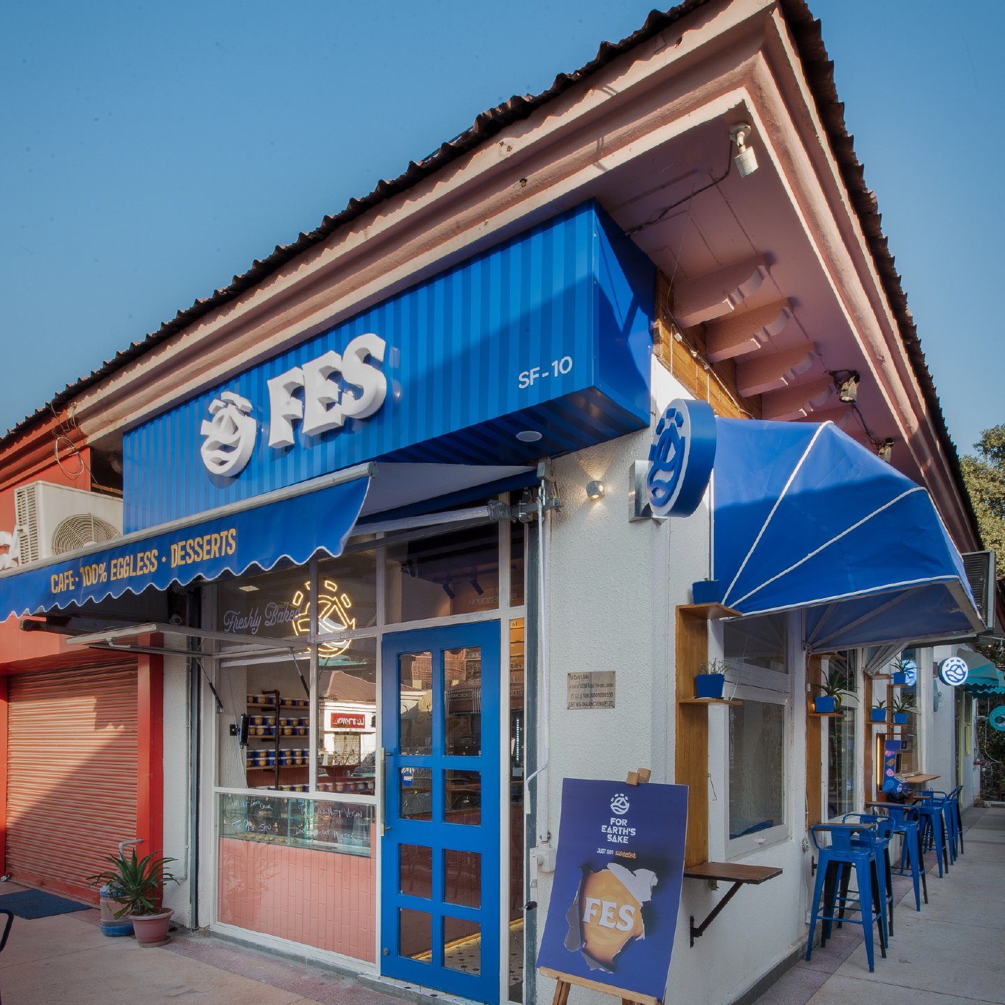 The FES storefront at Galleria Market — cobalt awnings, blue door, Freshly Baked neon